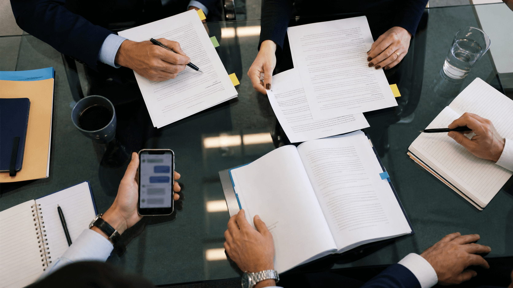Des salariés examinent des documents et un téléphone autour d’une table de réunion.